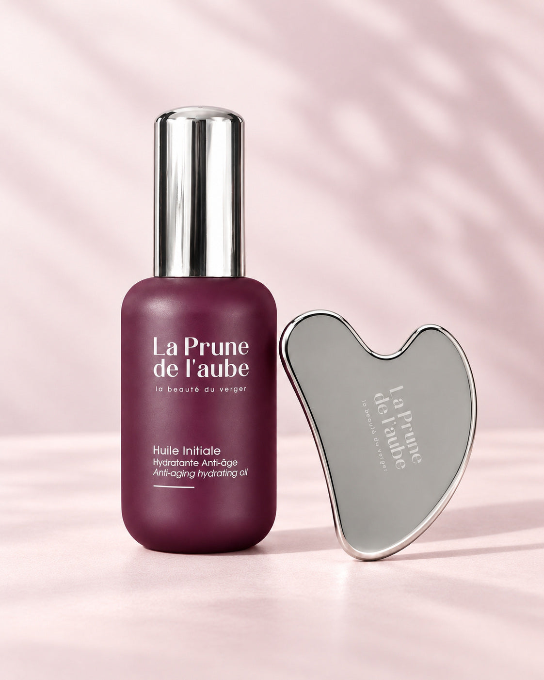 L’Huile Initiale et le Gua Sha en acier inoxydable réunis.