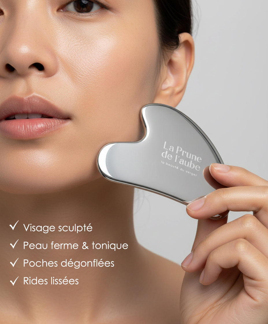 Femme utilisant un Gua Sha en acier inoxydable sur sa peau du visage pour massage et drainage