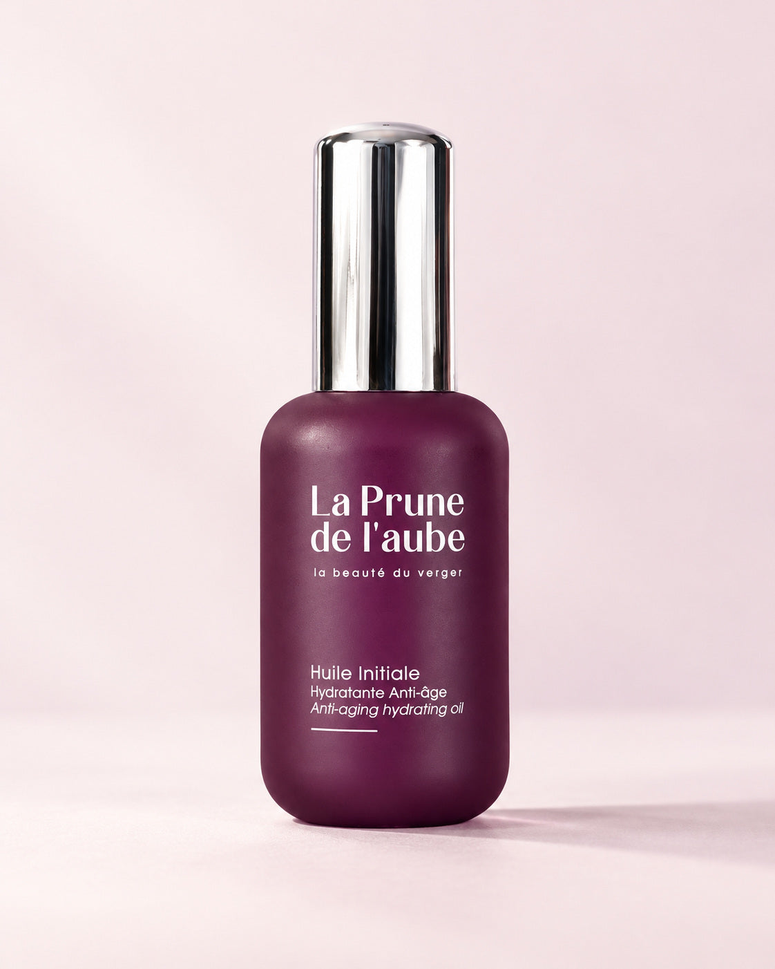 Flacon prune de L’Huile Initiale avec son capuchon argenté.