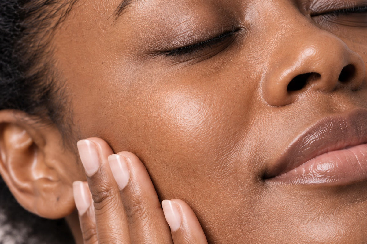 Très gros plan de doigts posés sur une joue lors d’un geste de massage du visage.