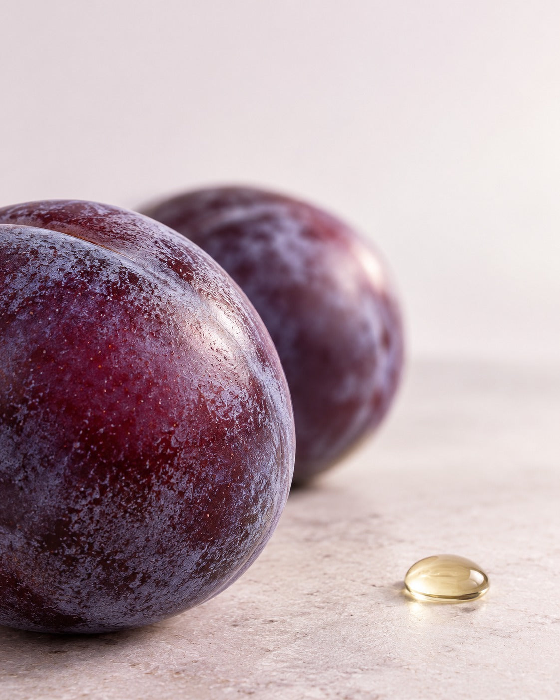Gros plan de prunes violettes à la peau veloutée sur un fond clair.
